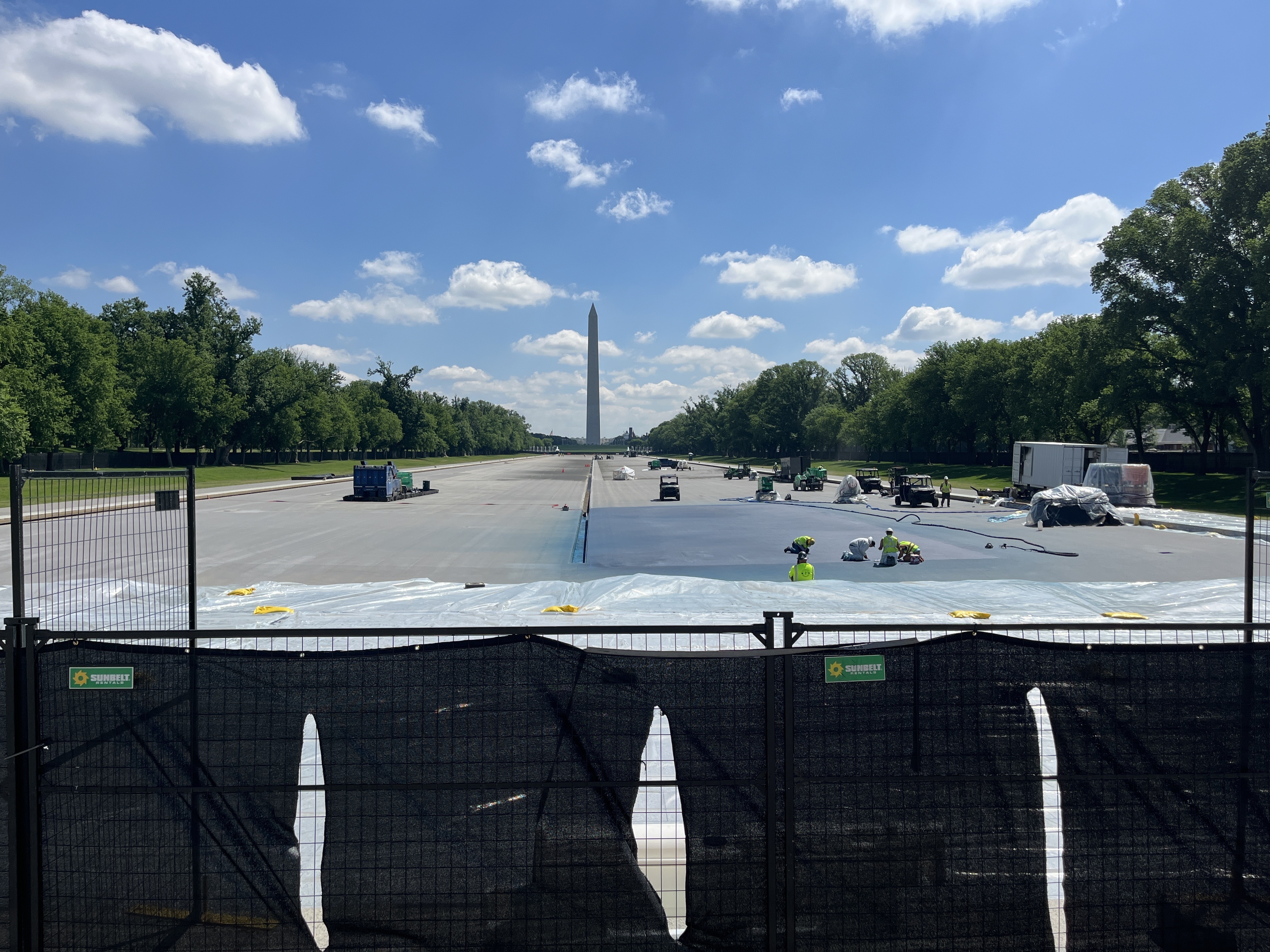 Workers paint a corner of the reflecting pool blue on Monday morning.